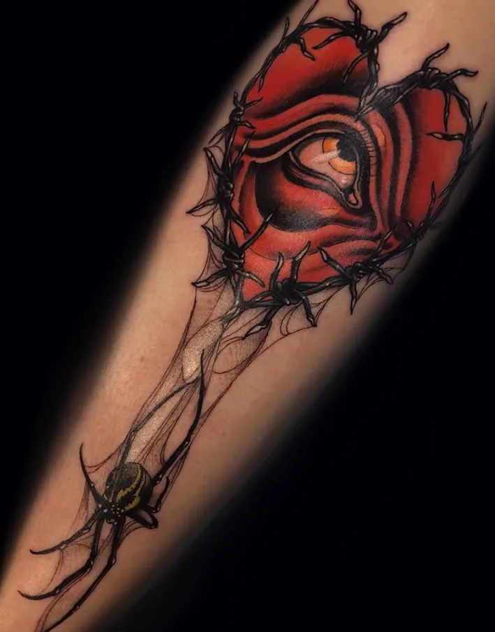 A red rose and heart bursting through cracked skin on the forearm in deep reds and black.